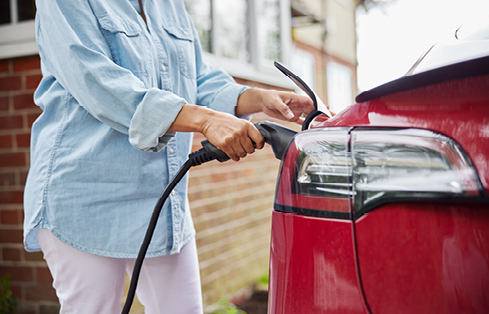 A person inserts a power cord into an electric car for charging