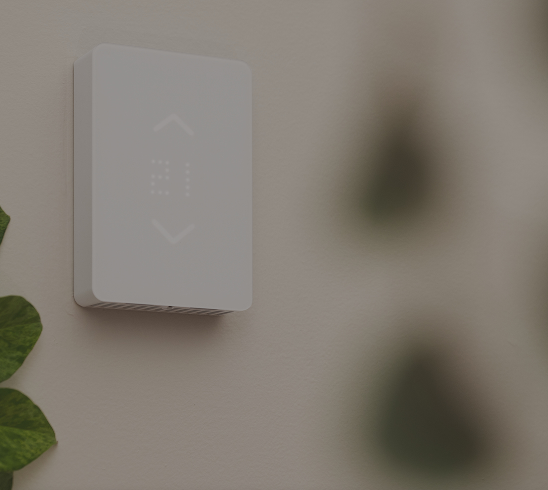 White coloured smart thermostat on a wall displaying the temperature 
