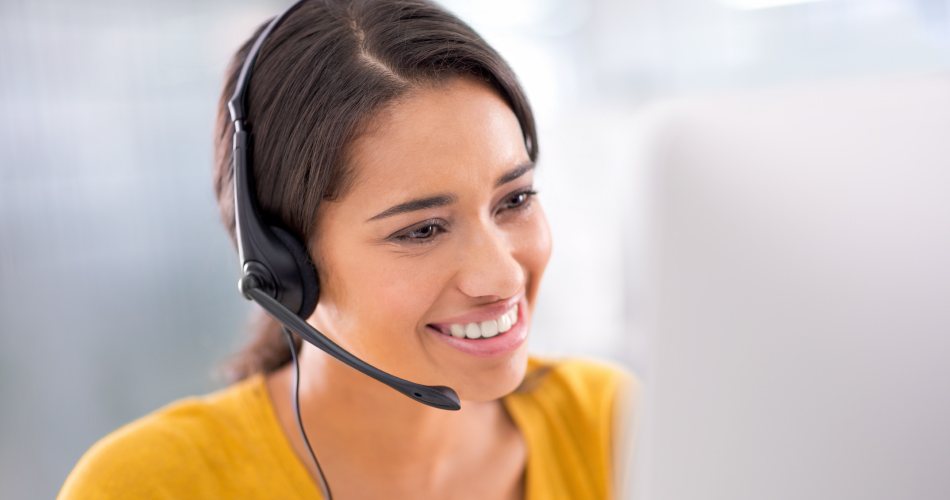 Photo of a young customer service representative wearing a headset at her computer