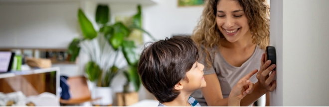 Woman and child adjusting a thermostat