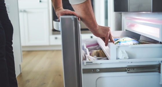 Hand putting food into the freezer.