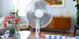 Female hand includes button on electric fan