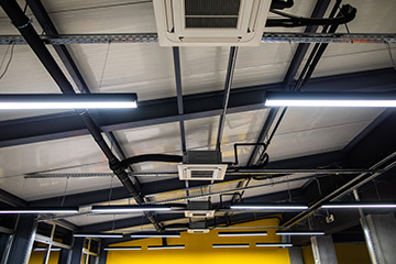 Ceiling in office space with air conditioner, lighting equipment, low angle view
