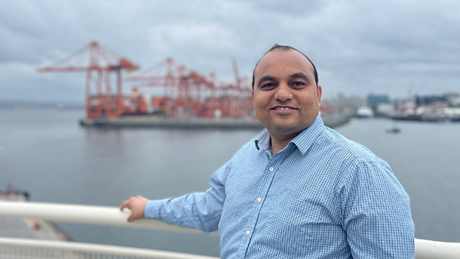 Manish smiling with the Port of Vancouver in the background