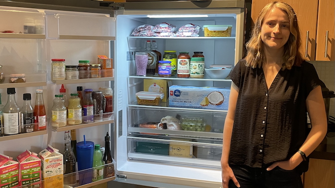Woman standing beside an open refrigerator