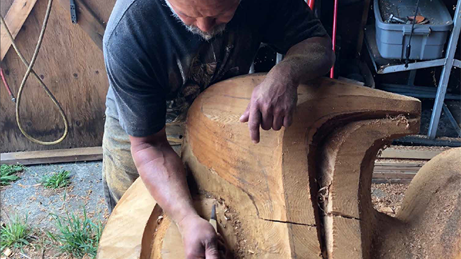 A person carving a totem.