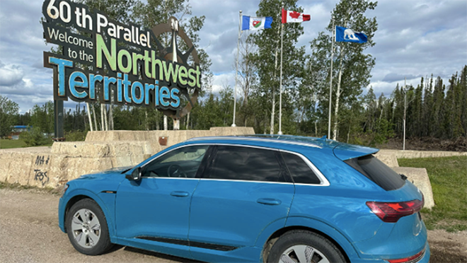 Soicher’s blue Audi e-tron with a Northwest Territories sign in the background.