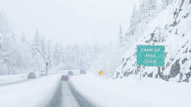 Snowy conditions on the road with a signage: chain up area