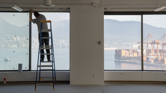 Man on a ladder installing a window.