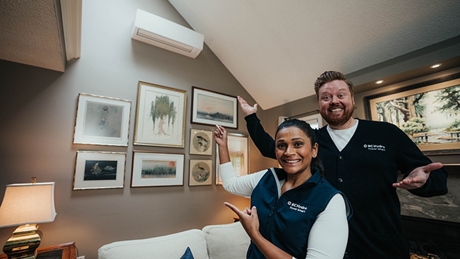 Dave and Jaclyn gesturing towards a heat pump
