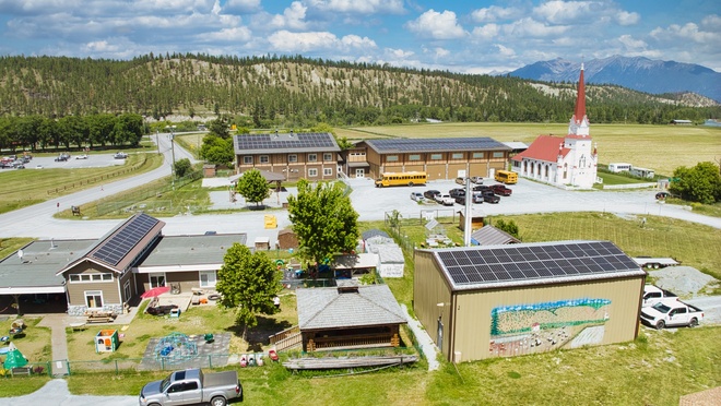 Aerial view of a rural community with multiple buildings featuring rooftop solar panel installations.