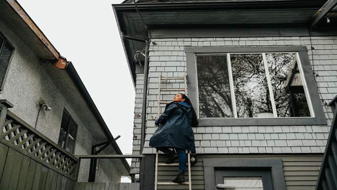 BC Hydro spokesperson Jaclyn standing on a ladder outside a home.