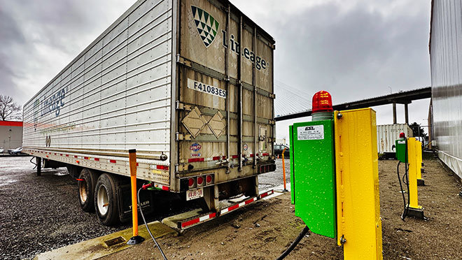 A refrigerated truck trailer stays plugged in outside of a warehouse