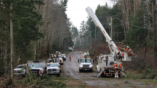 BC Hydro crews work along a rural road to restore power and clear storm debris following severe weather damage.