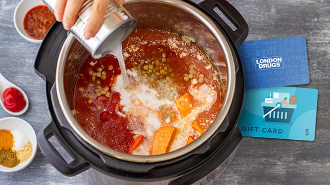 A soup being cooked in a pressure cooker, with a London Drugs and grocery gift card.