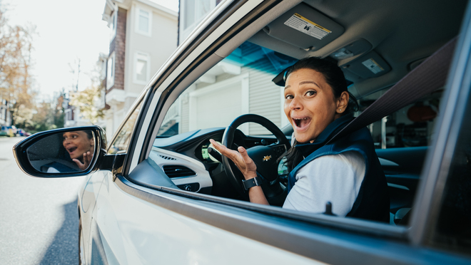 BC Hydro spokesperson, Jaclyn, sits in the drivers seat of an EV. An excited expression on her face.