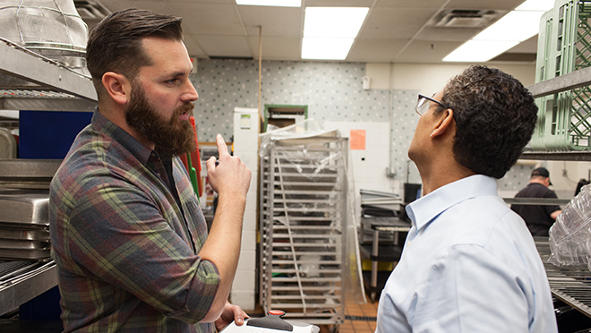 A client and a holding a clipboard contactor discussing in a commercial kitchen