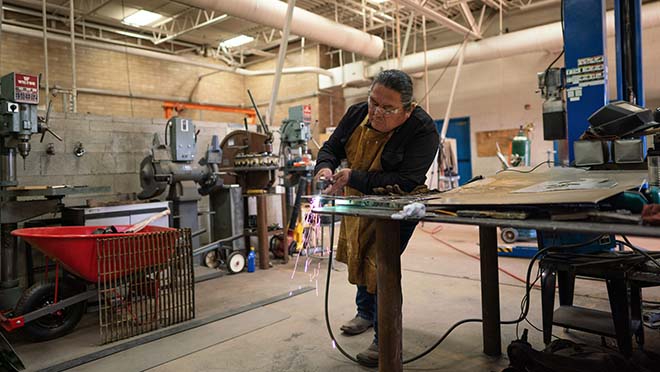 Male holding a metal cutter in a workshop