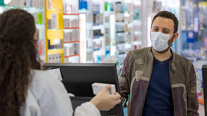 Image of a shop worker and customer wearing masks and following social distance guidelines Image of a shop worker and customer wearing masks and following social distance guidelines